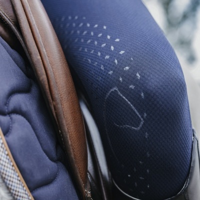 Calças de equitação azul com selo branco, sela de couro castanho e almofada azul