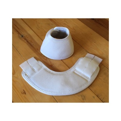 Conjunto de proteção branco em tecido macio com fechos de velcro sobre madeira clara