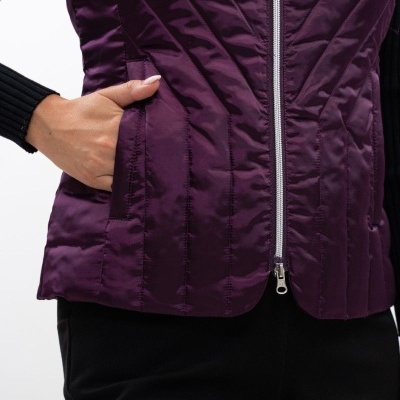 Colete acolchoado roxo com fecho de correr e bolso vestindo camisa preta e calças pretas