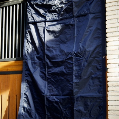 Cortina azul escura com ilhós pendurada em porta de madeira com grades metálicas.