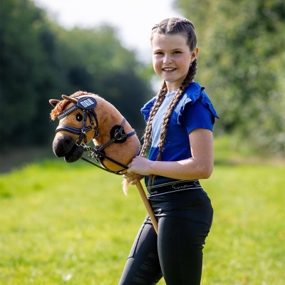 Menina com brinquedo de cabe a de cavalo e roupa azul e preta em relvado
