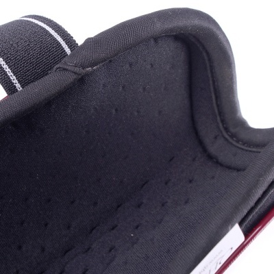 Proteção de pulso preta almofadada com tira ajustável e detalhe branco.