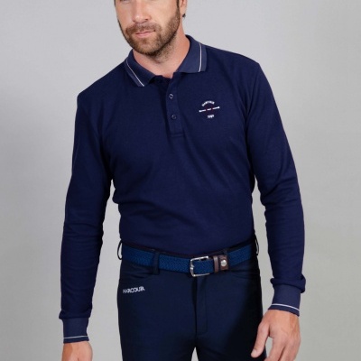 Homem com polo azul escuro de manga comprida e calças justas azuis escuras com cinto azul