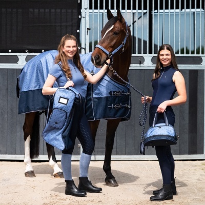 Duas mulheres em roupa de equitação azul com cavalo e acessórios em estábulo
