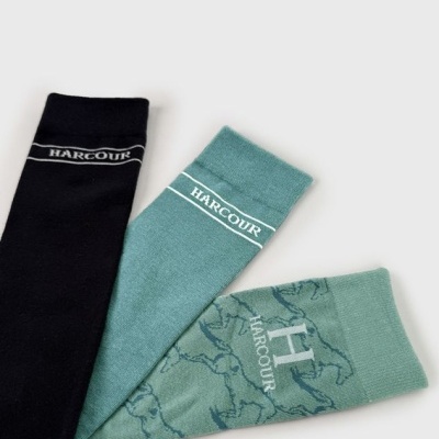 Três pares de meias Harcour em preto e verde água com diferentes padrões e logos visíveis.