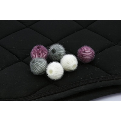 Seis bolas pequenas de lã colorida sobre tecido preto acolchoado.