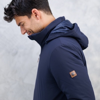 Homem com jaqueta azul escura com capuz e detalhe em couro no braço