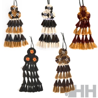 Cinco pendentes decorativos em fibras naturais de várias cores com franjas e nós.