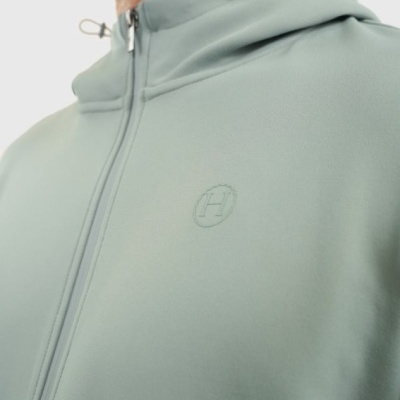 Casaco verde claro com capuz e fecho de correr, detalhe do logótipo H no peito