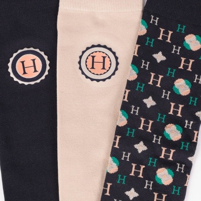 Três pares de meias com logótipo e padrão de letras H em diversas cores.