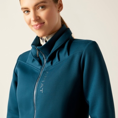 Mulher com casaco azul escuro com fecho e escrita 'IMPACT'.