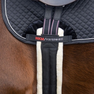 Sela de equitação preta sobre cavalo castanho com mantal acolchoado e tiras com proteção de pele sintética.