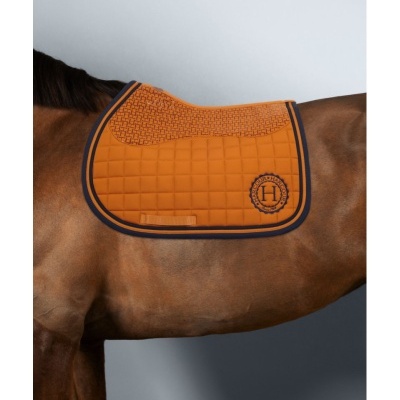 Sela de cavalo cor de ferrugem acolchoada com padrão quadriculado e bordado H