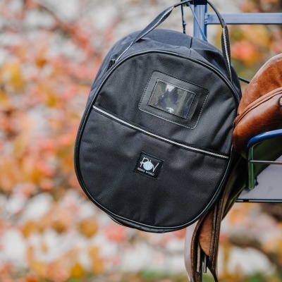Mala azul escura de tecido pendurada num suporte azul metálico com sela e acessórios de equitação