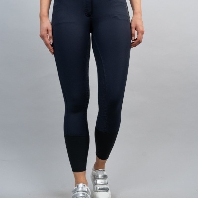 Calças justas azul escuro com bolsos castanhos e parte inferior preta, modelo com ténis brancos prateados