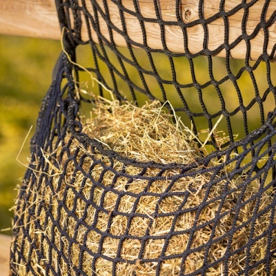 Rede preta de corda pendurada numa estrutura de madeira com feno