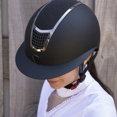 Capacete de equitação preto com detalhes metálicos e ventilação frontal
