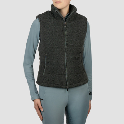 Colete acolchoado preto tipo lã ovelha com fecho e bolsos, usado sobre roupa térmica azul clara.