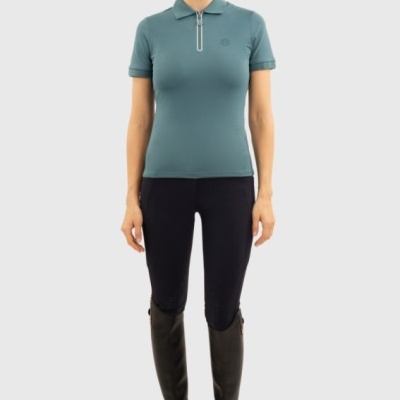 Mulher de pé com polo azul, calças pretas e botas pretas