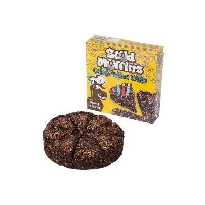 Bolo redondo escuro com fatias ao lado da embalagem amarela Stod Muffins Celebration Cake