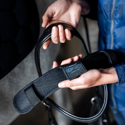 Equipamento equestre preto com etiqueta IONIC CERAMIC IONIZED e pessoa segurando