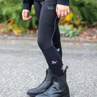 Perna de criança com leggings pretas e botas pretas ao ar livre