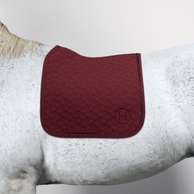 Manta de sela bordô acolchoada com padrão geométrico sobre cavalo branco