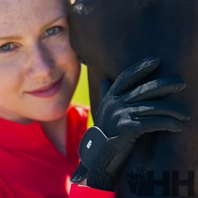 Mão com luva preta com textura segurando um animal preto, pessoa com casaco vermelho ao fundo