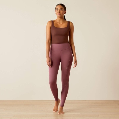 Mulher com top castanho e leggings rosa em fundo neutro