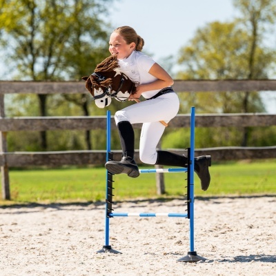 Menina a saltar barreira com cavalo de brinquedo