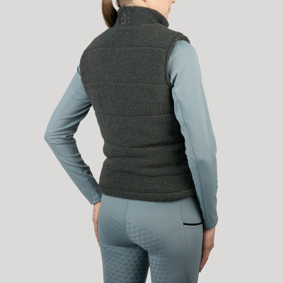 Colete felpudo cinzento escuro usado por mulher de costas com roupa desportiva azul clara