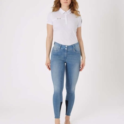 Mulher com jeans azuis de corte justo e polo branca com logótipo em fundo branco.