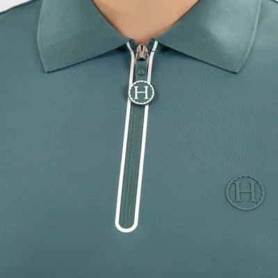 Polo verde-azulado com fecho de correr e logo H em relevo no peito