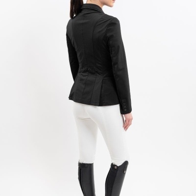 Mulher de costas com blazer preto, calças brancas e botas pretas altas em fundo branco.