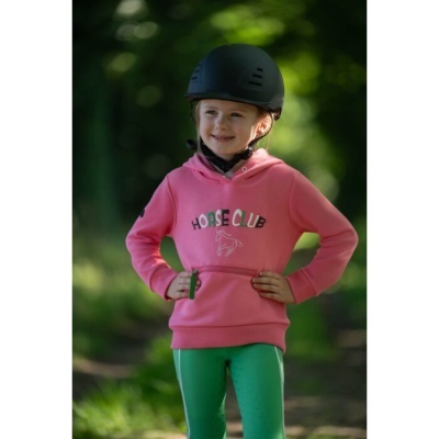 Criança com capacete preto e camisola rosa com texto Horse Club