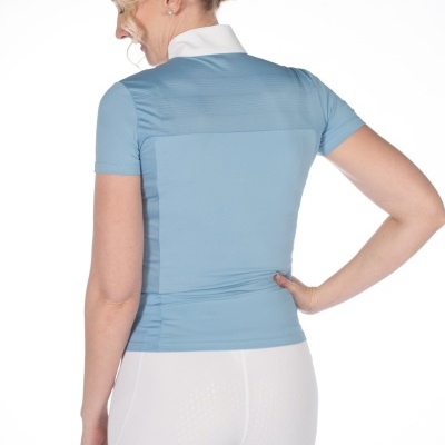 Mulher de costas usando blusa azul clara de manga curta e calças justas brancas