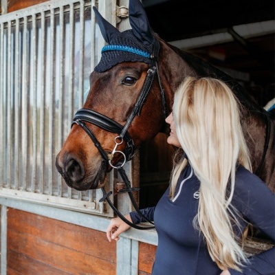 Mulher loira com cavalo castanho em estábulo