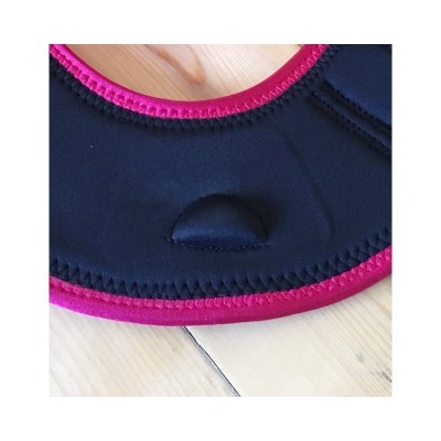 Detalhe de tecido preto com costura rosa em superfície de madeira clara