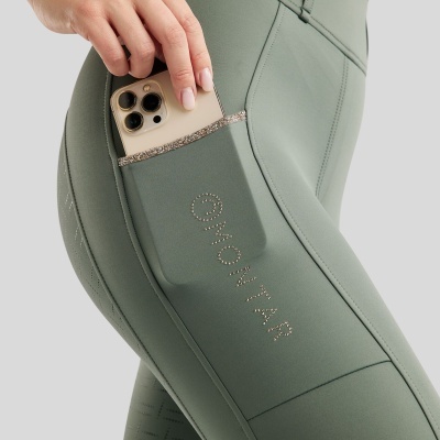 Leggings verdes com bolso lateral e telemóvel dourado a ser colocado no bolso