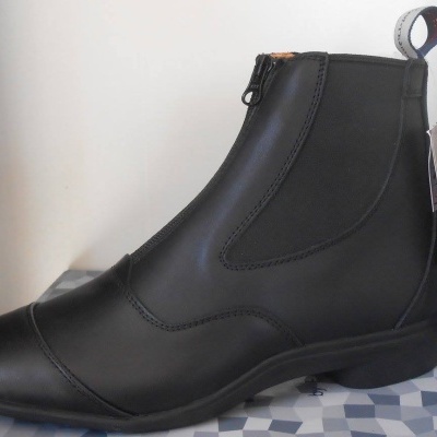 Botim preto em couro com fecho zíper e costuras visíveis sobre padrão geométrico