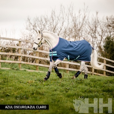Cavalo branco com manta azul escuro e proteções nas patas num campo verde