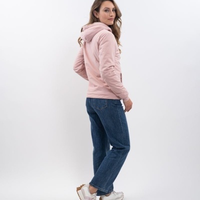 Mulher com capuz rosa, calças de ganga e sapatilhas em fundo branco