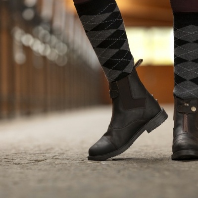 Botas de pele preta com meias cinzentas com padrão quadriculado em ambiente interior