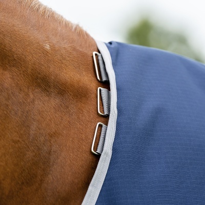 Cobertura azul para cavalo com borda cinza e fivelas metálicas prateadas