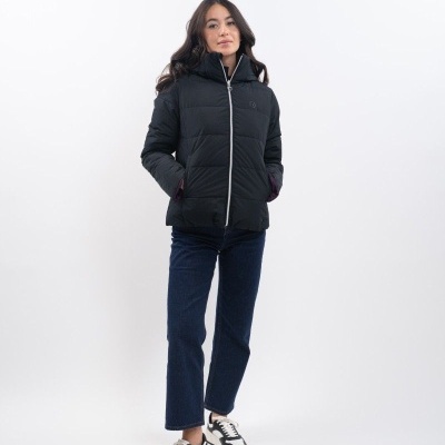 Mulher a usar casaco acolchoado preto, calças azuis e sapatilhas brancas e pretas