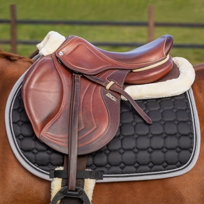 Sela de equitação castanha em pele com detalhes brancos sobre cavalo