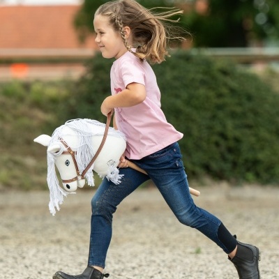 Criança a correr com cavalo a pau branco e roupa casual