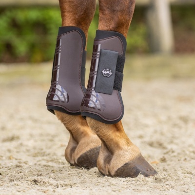 Botas protetoras castanhas e pretas nas patas traseiras de cavalo