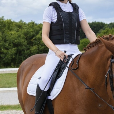 Mulher a montar cavalo castanho com equipamento de equitação preto e branco