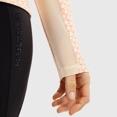 Detalhe de roupa desportiva com perna preta e manga comprida bege com padrão cor de rosa.